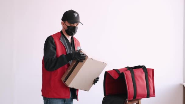 Entrega homem em equipamento de proteção é embalagem takeaway pizza — Vídeo de Stock
