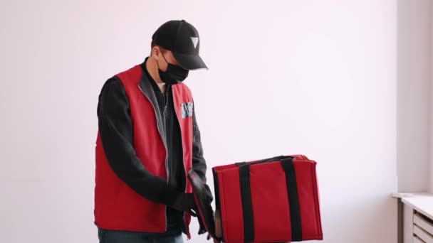 Delivery man in protective equipment is packing takeaway pizza — Stock Video