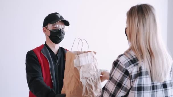 Курьер ныряет с бумажным пакетом к женщине в маске — стоковое видео