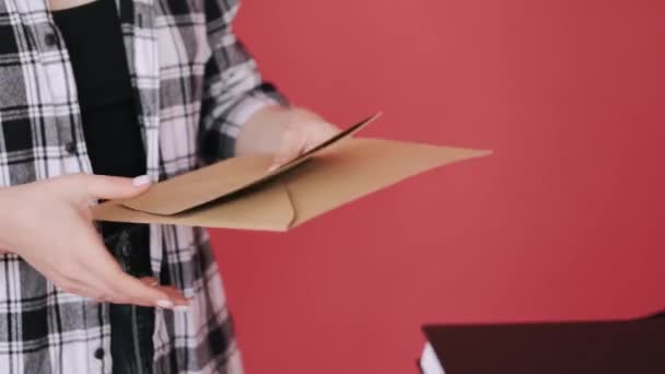 Mulher com uma máscara está recebendo uma parcela de envelopes de papel artesanal de um entregador — Vídeo de Stock