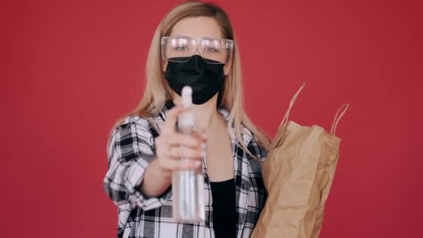 Kvinna i skyddsglasögon och mask sprutar antiseptisk — Stockvideo