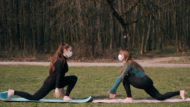 Las mujeres del deporte están haciendo ejercicio del yoga de la mañana afuera en esteras — Vídeo de stock