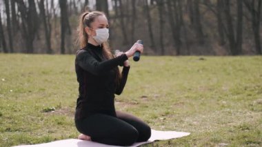 Koruyucu maskeli atletik kadın halterlerle egzersiz yapıyor.