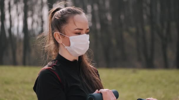 Atletische vrouw in een beschermend masker doet oefening met halters — Stockvideo