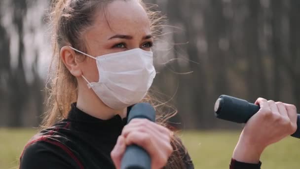 保護マスクのアスレチック女性はダンベルと運動をしている — ストック動画