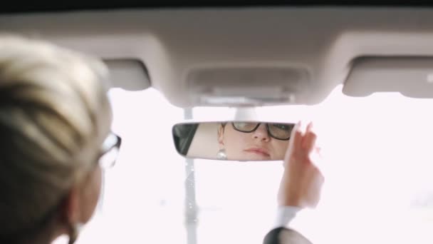 Een zakenvrouw rijdt in een auto en rijdt achteruit. — Stockvideo