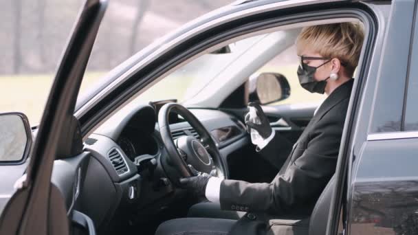 Женщина в одноразовой маске дезинфицирует свою машину антисептиком. — стоковое видео