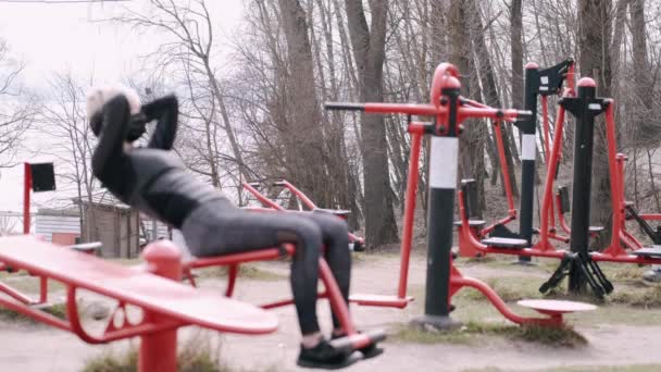 La mujer deportiva con una máscara protectora está haciendo ejercicio en un parque — Vídeos de Stock