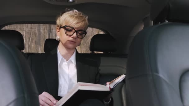 Une femme d'affaires en lunettes travaille dans une voiture — Video