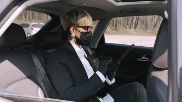 Une femme d'affaires en lunettes travaille dans une voiture — Video