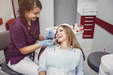 Güzel kız dişçi ofisinde oturuyor.