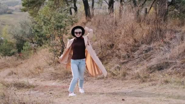 Portrait of stylish woman in coat and hat moving in forest — Stock Video