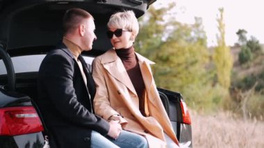 Bagajda oturan çift birbirlerine bakıyorlar.