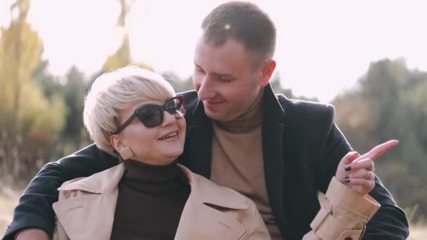 Portret van man en vrouw die samen zitten en elkaar omhelzen in het bos — Stockvideo