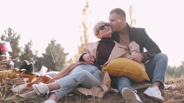 Retrato de marido y mujer sentados juntos y besándose en el bosque — Vídeos de Stock