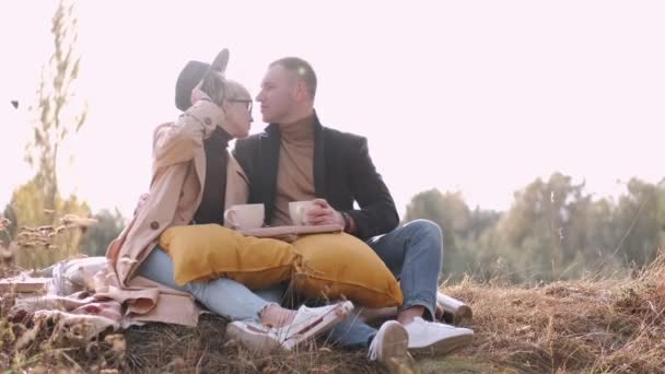 Чоловік і дружина сидять разом і п'ють чай в лісі — стокове відео
