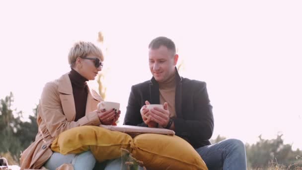 Par som håller muggar medan de dricker te utomhus — Stockvideo
