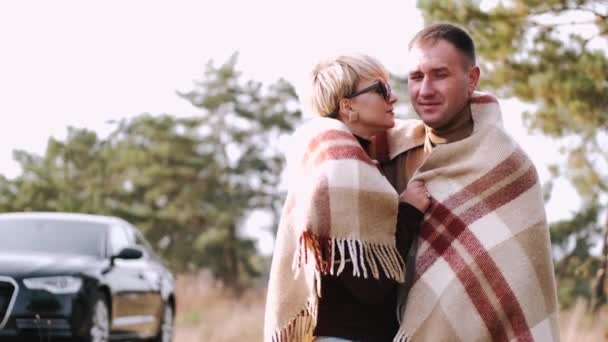 Retrato de pareja cubierta de manta abrazándose en el bosque — Vídeos de Stock