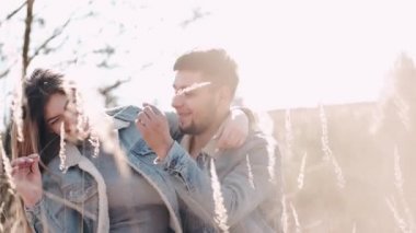 Sevgili bir çift buğday tarlasında gün batımında öpüşüyor.