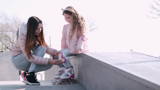 Мать помогает своему ребенку носить роликовые коньки — стоковое видео
