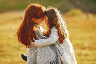 Anne ve küçük kızı sonbahar tarlasında oynuyorlar.