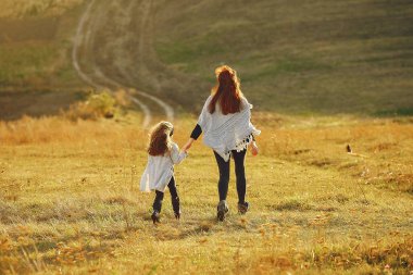 Anne ve küçük kızı sonbahar tarlasında oynuyorlar.