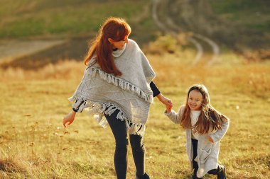Anne ve küçük kızı sonbahar tarlasında oynuyorlar.