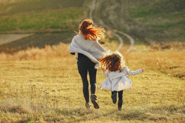 Anne ve küçük kızı sonbahar tarlasında oynuyorlar.