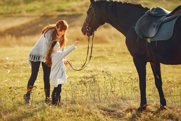 Mãe e filha em um campo brincando com um cavalo — Fotografia de Stock