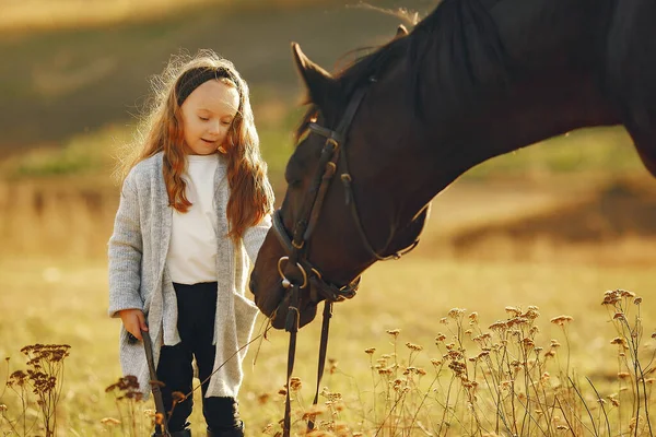 Petite fille mignonne dans un champ d'automne avec cheval — Photo