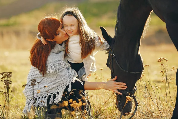 Moeder en dochter in een veld spelen met een paard — Stockfoto