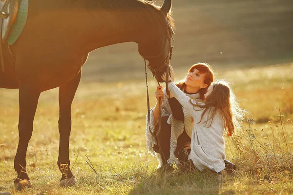 Moeder en dochter in een veld spelen met een paard — Stockfoto