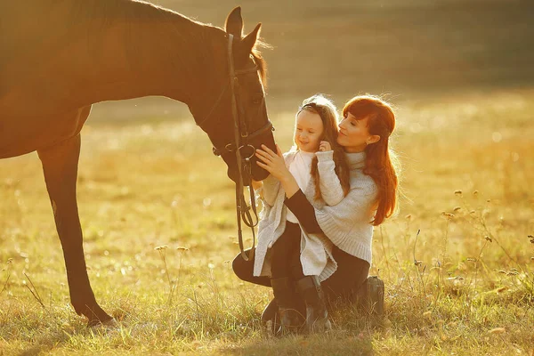 Mother and daughter in a field playing with a horse — Stock Photo, Image