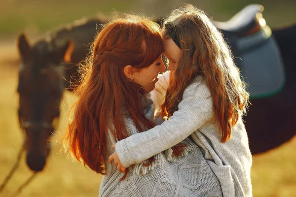 Mor och dotter på ett fält leker med en häst — Stockfoto