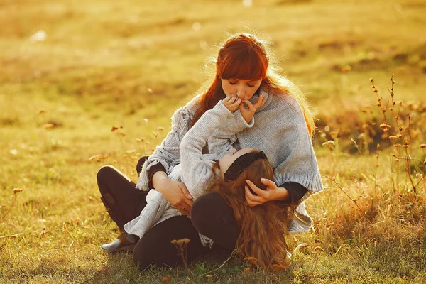 Mor med liten dotter som leker på ett höstfält — Stockfoto
