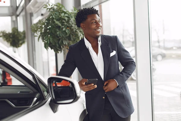 Hombre negro guapo y elegante en un salón de coches — Foto de Stock