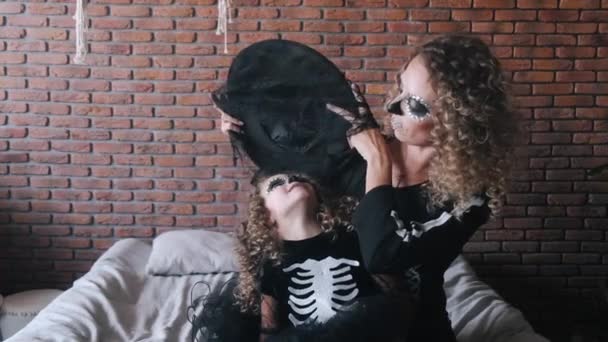 Мать и дочь с вьющимися волосами сидят на диване в костюмах — стоковое видео