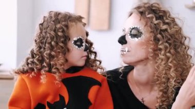Anne-kız Cadılar Bayramı kostümleri birbirine bakıyor.