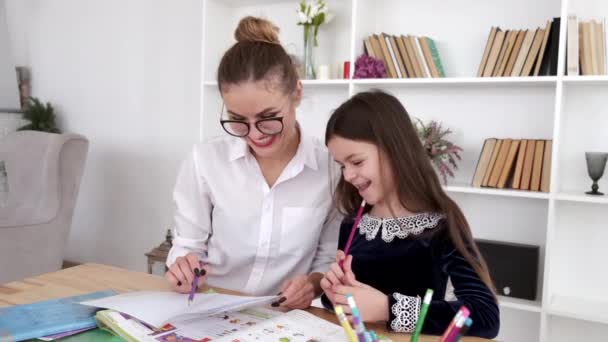 Μητέρα με γυαλιά βοηθώντας μελαχρινή κόρη να κάνει την εργασία στο σπίτι — Αρχείο Βίντεο