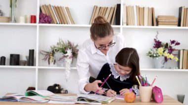 Genç öğretmen esmer kıza kütüphanede ödev yapmasına yardım ediyor.