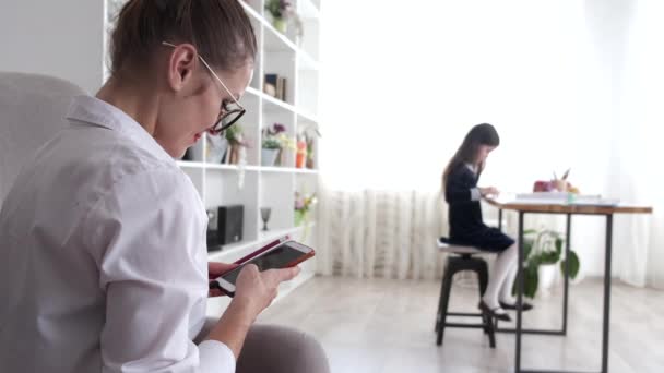 Matka používá telefon, zatímco dítě dělá domácí úkoly — Stock video