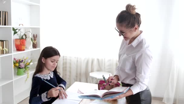 Young teacher explaining exercise to schoolgirl in modern library — Stock Video