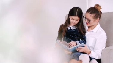 Öğrenci kız, modern dairede annemle kitap okuyor.