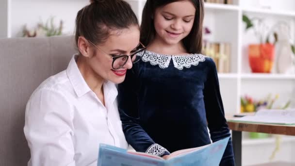 Portret matki i brunetki czytających podkład w domu — Wideo stockowe