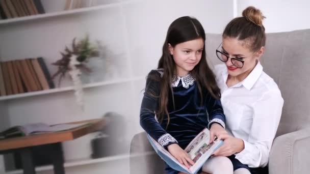 Schoolmeisje lezen boek met moeder in modern appartement — Stockvideo