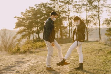 Bahar ormanında maskeli insanlar dikiliyor.