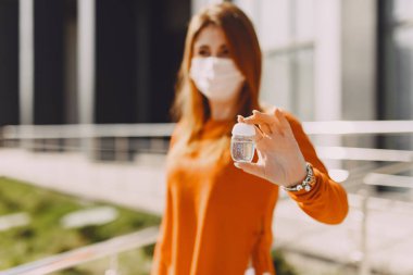 Maskeli kadın sokakta duruyor.