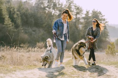 Bir bahar tarlasında köpekli iki şık kız.