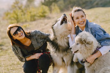 Bir bahar tarlasında köpekli iki şık kız.