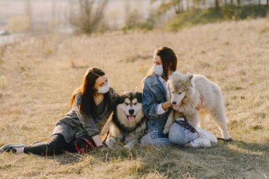 Bir bahar tarlasında köpekli iki şık kız.
